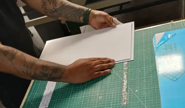 Manos cortando lámina reflejante sobre la mesa de trabajo del taller de Nyne Print